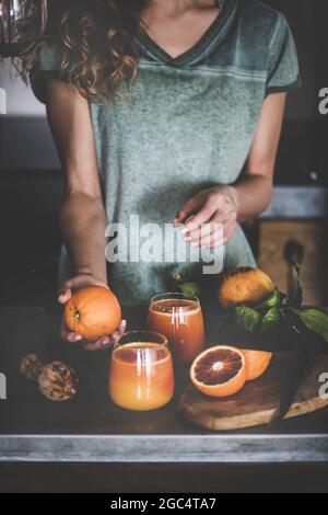 Frau, die frisches Blut orange Saft oder Smoothie in der Küche Stockfoto