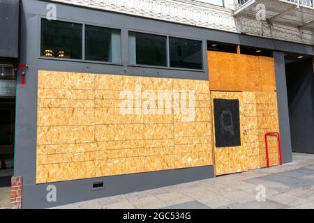 Außenansicht eines permanent geschlossenen Geschäfts, Geschäfts, Restaurants, das mit Sperrholzplatten verkleidet ist, um unbefugten Zugriff durch Hausbesetzer, Plünderer oder zu verhindern Stockfoto