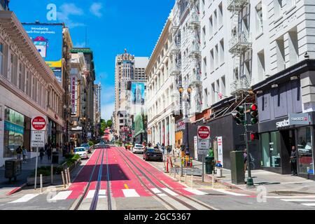 Blick auf eine leere Seilbahn auf der rot gestrichenen Powell Street, die an sonnigen Tagen von der Kreuzung Ellis Street bergauf fährt. - San Francisco, Kalifornien, Stockfoto
