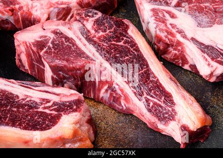 Bio rohes Rindfleisch frisches Fleisch, auf altem dunklen rustikalen Hintergrund, T-Knochen geschnitten Stockfoto