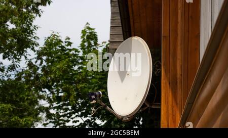 Satellitenantenne im Haus. Weiße Antenne für den Empfang des TV-Signals. Satellitenkommunikation im Dorf. Stockfoto