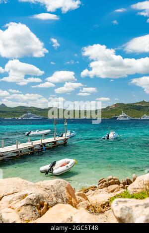 (Selektiver Fokus) atemberaubender Blick auf den Strand von Capriccioli, der an einem sonnigen und windigen Tag von einem türkisfarbenen und rauhen Wasser umspült wird. Stockfoto