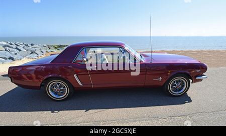 Classic Purple Ford Mustang geparkt am Strand und Meer im Hintergrund. Stockfoto