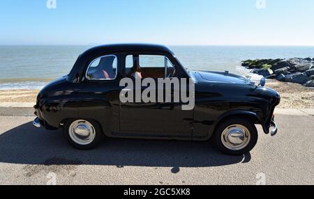 Classic Black 2 Door Baby Austin A30 geparkt am Strandpromenade Strand und Meer im Hintergrund. Stockfoto