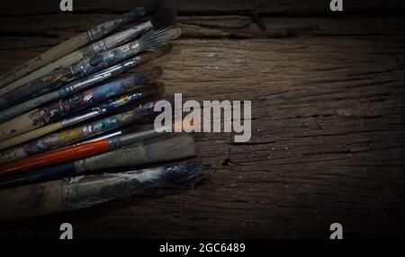 Wasserfarben-Ausrüstung Pinsel verschiedener Größen, Farbpaletten auf altem Holzhintergrund. Stockfoto