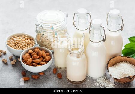 Alternative Arten von veganen Milchsorten in Glasflaschen auf betontem Hintergrund. Draufsicht Stockfoto