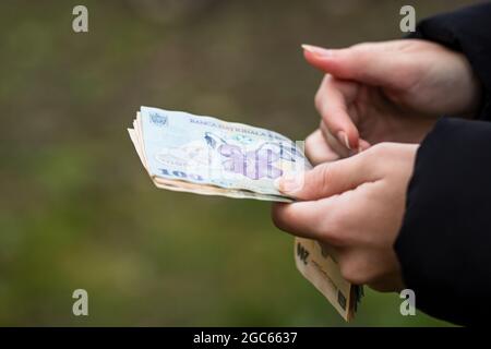 Flache Aufnahme mehrerer rumänischer Leu-Banknoten, die von einer Frau gehalten werden Stockfoto