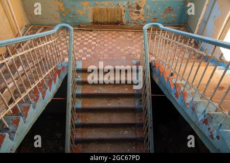 Die Leiter im alten zerstörten und verlassenen Gebäude des sowjetischen Krankenhauses. Draufsicht Stockfoto