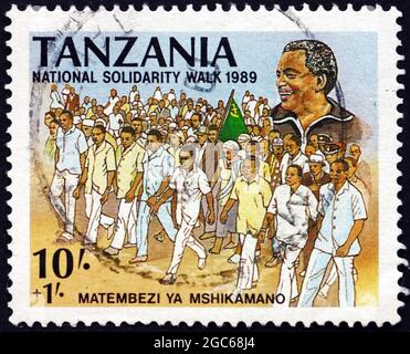 TANSANIA - UM 1989: Eine in Tansania gedruckte Briefmarke, die dem Nationalen Solidaritätsmarsch gewidmet ist, Präsident Ali Hassan Mwinyi, um 1989 Stockfoto