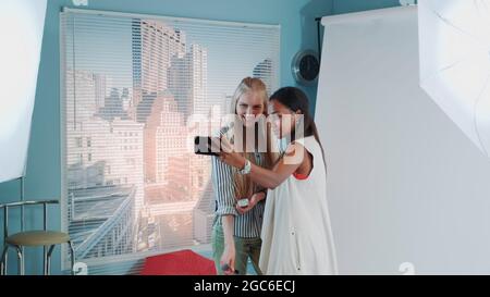 Backstage des Fotoshootings: Attraktives schwarzes Modell macht selfie mit hübschem Make-Up-Künstler. Sie lächeln und haben Spaß. Stockfoto