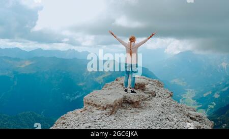 Junge Frau mit ausgestreckten Armen genießen die Schönheit der Natur auf Bergfelsen. Fantastische Aussicht auf die Landschaft. Stockfoto