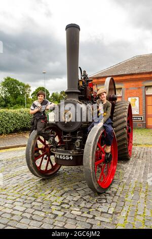 Kidderminster, Worcs, Großbritannien. August 2021. Die Brüder Edward und Arthur Marriott, 10 und 9, sitzen auf ihrem Fowler D2-Traktor, der auf der Vintage Transport Extravaganza am Bahnhof Severn Valley, Kidderminster, Worcs, stattfindet. Kredit: Peter Lopeman/Alamy Live Nachrichten Stockfoto