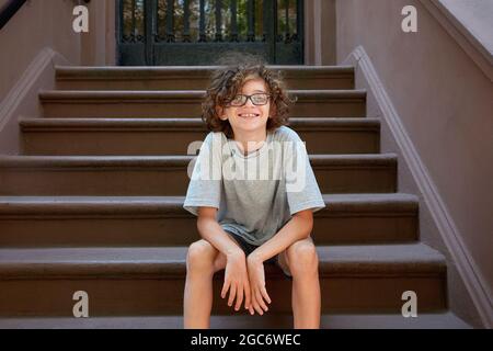 USA, New York, New York City, Junge, der auf einer Treppe vor dem Gebäude sitzt Stockfoto