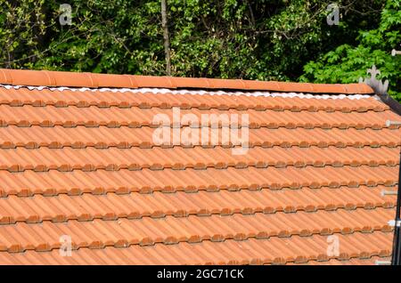Haus mit doppelt geneigtem Dach in Fliesen, offensichtlich die Ridge-Linie und Hüllen unter Ridge Fliesen. Stockfoto