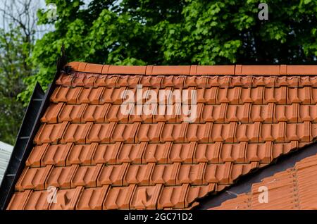 Haus mit doppelt geneigtem Dach in Fliesen, offensichtlich die Ridge-Linie und Hüllen unter Ridge Fliesen. Stockfoto