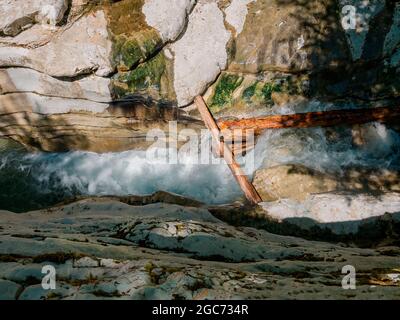 Ein schäumender, turbulenter Fluss fließt in einer engen Schlucht zwischen den Schluchten durch große Baumstämme. Draufsicht Stockfoto