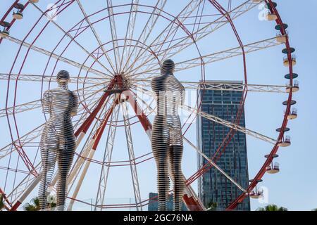 Batumi, Georgia - 2. Juli 2021: Ali und Nino Statue und das Riesenrad in Batumi, Adjara, Georgia. Sich aufeinander zu bewegen berühmte Skulpturen von Mann und Frau in der Liebe. Beliebte Touristenattraktion Stockfoto