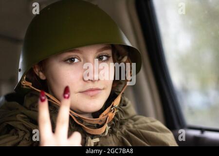 Ein Militärhelm des Zweiten Weltkriegs auf dem Kopf eines Soldaten. Wiederherstellung des Bildes eines Soldaten in Russland. Ein Mädchen in Militäruniform. Stockfoto
