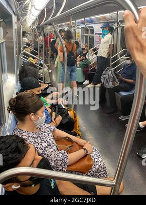 Maskierte Pendler fahren im Juli 2021 mit einem U-Bahn-Zug in New York City, als gehofft wurde, dass die Pandemie vorbei sein würde, aber sie scheint sich fortzusetzen. Die Menschen sind es leid, mit Halbatem zu leben. Stockfoto