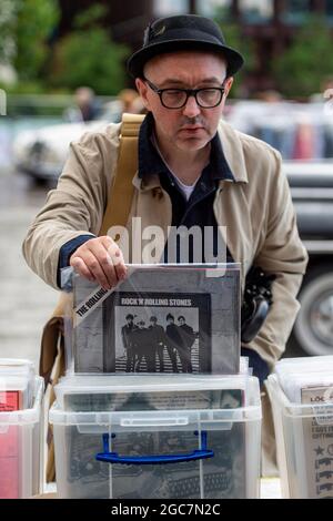 London, Großbritannien. 7. August 2021. Beim Classic Car Boot Sale in Granary Square, King’s Cross, stösst ein Mann auf Vinyl. Die Veranstaltung feiert alle Dinge Vintage von Mode und Schmuck zu Haushaltswaren und Vinyl-Schallplatten. Mehr als 100 Oldtimer sind ebenfalls zu sehen. Kredit: Stephen Chung / Alamy Live Nachrichten Stockfoto