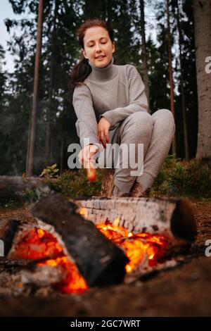 Eine Frau auf einem Picknick im Wald am Feuer Stockfoto