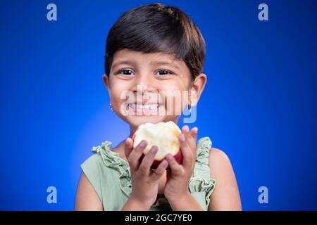 Portrait von Mädchen Kind hält Apfel auf blauem Hintergrund - Konzept der gesunden Ernährung und Lebensstil Stockfoto