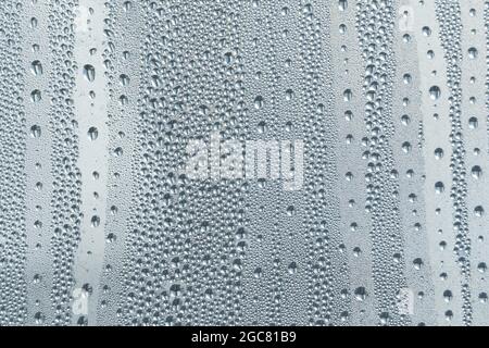 Nach dem Regen ruht ein kleiner Regentropfen auf dem Glas. Regentropfen Auf Dem Glas. Regentropfen auf dem Fenster. Blauton. Abstrakter Hintergrund. Stockfoto