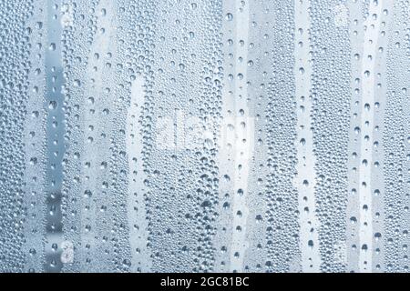 Nach dem Regen ruht ein kleiner Regentropfen auf dem Glas. Regentropfen Auf Dem Glas. Regentropfen auf dem Fenster. Blauton. Abstrakter Hintergrund. Stockfoto