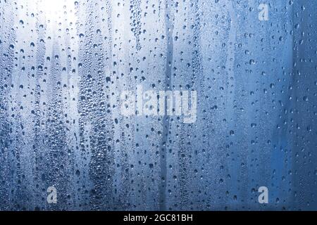 Nach dem Regen ruht ein kleiner Regentropfen auf dem Glas. Regentropfen Auf Dem Glas. Regentropfen auf dem Fenster. Blauton. Abstrakter Hintergrund. Stockfoto