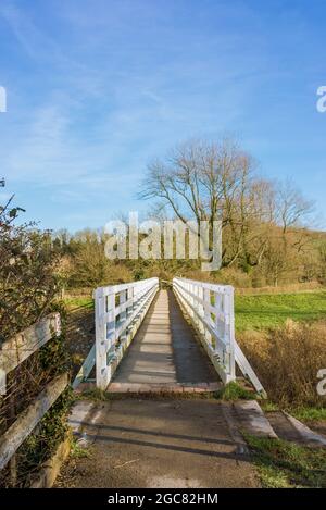 Die Fußgängerbrücke über den Cuckmere River in Alfriston, Großbritannien, auf dem South Downs Way, einem Nationalpfad von Eastbourne nach Winchester, an einem sonnigen Wintertag. Stockfoto