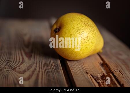 Saftige gelbe Birne auf einem hölzernen Hintergrund aus alten Brettern in einem niedrigen Schlüssel. Reife Birne für eine gesunde Ernährung. Stockfoto