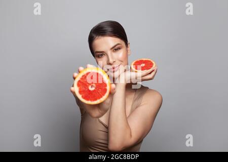 Hübsche Frau mit köstlicher Grapefruit im Porträt ihrer Arme Stockfoto