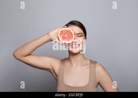 Glückliche junge Frau mit der Hälfte der Grapefruit Stockfoto