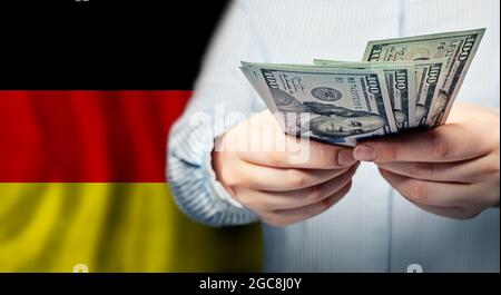 Hände, die eine Banknote mit US-Dollar auf deutscher Flagge halten Stockfoto