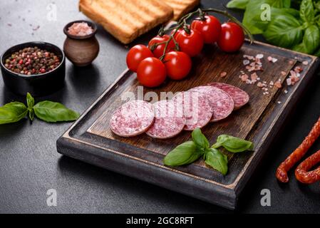 Spanische getrocknete Wurstsalami auf einem dunklen Betongrund. Zubereitung von leckeren frischen Sandwiches Stockfoto