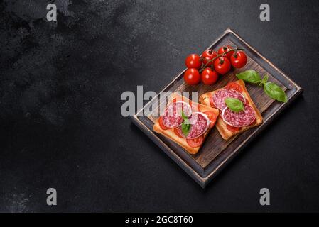 Spanische getrocknete Wurstsalami auf einem dunklen Betongrund. Zubereitung von leckeren frischen Sandwiches Stockfoto