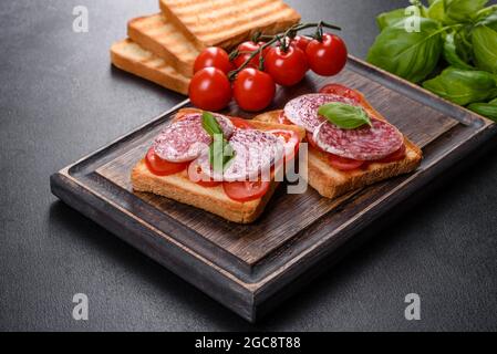 Spanische getrocknete Wurstsalami auf einem dunklen Betongrund. Zubereitung von leckeren frischen Sandwiches Stockfoto