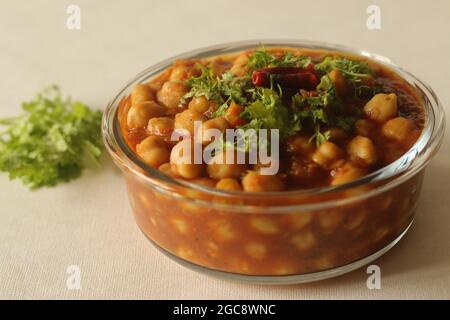 Kichererbsen in einer dicken Soße aus Zwiebeln, Tomaten und Gewürzen. Serviert in einer Glasschüssel. Aufgenommen auf weißem Hintergrund. Stockfoto