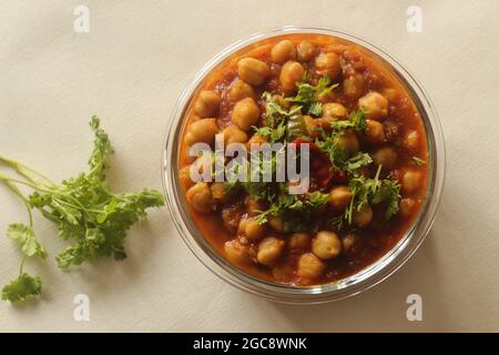 Kichererbsen in einer dicken Soße aus Zwiebeln, Tomaten und Gewürzen. Serviert in einer Glasschüssel. Aufgenommen auf weißem Hintergrund. Stockfoto