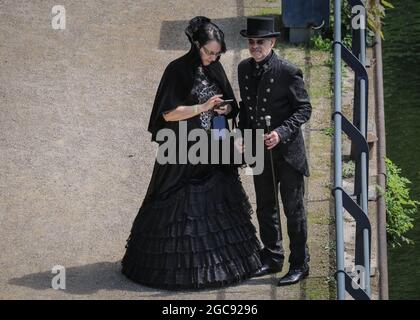 Schiffshebewerk Henrichenburg, Waltrop, Deutschland. August 2021. Die viktorianische Ära trifft mit einem Paar in schönen schwarzen Outfits auf das Zeitalter der modernen Technologie. Steampunk-Fans und Besucher, viele in voll retro-futuristischen Kostümen und Steampunk-Outfits, treffen sich zum ´Steampunk Jubilee Market´ Festival am historischen Wahrzeichen der Henrichenburg-Seilbahn, Teil des Waltrop-Schlossparks am Dortmund-Ems-Kanal, heute ein Industriemuseum. Das alte Eisengerüst, die Kontrolltürme, Maschinenhäuser und das Museum bilden eine stimmungsvolle Kulisse für das Festival. Kredit: Imageplotter/Alamy Live Nachrichten Stockfoto