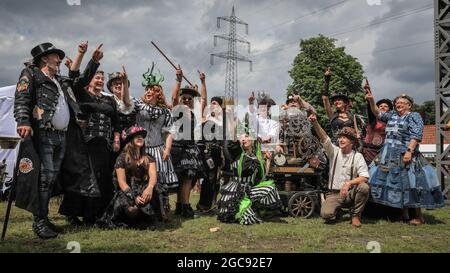 Schiffshebewerk Henrichenburg, Waltrop, Deutschland, 7. August 2021. Die Teilnehmer posieren zusammen mit Mitgliedern des Steampunk ´Stammtisch´für eine Gruppenaufnahme. Steampunk-Fans und Besucher, viele in voll retro-futuristischen Kostümen und Steampunk-Outfits, treffen sich zum ´Steampunk Jubilee Market´ Festival am historischen Wahrzeichen der Henrichenburg-Seilbahn, Teil des Waltrop-Schlossparks am Dortmund-Ems-Kanal, heute ein Industriemuseum. Das alte Eisengerüst, die Kontrolltürme, Maschinenhäuser und das Museum bilden eine stimmungsvolle Kulisse für das Festival. Stockfoto