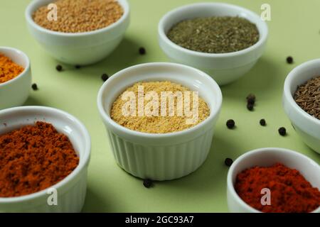 Set aus verschiedenen Gewürzen in Schüsseln auf grünem Hintergrund Stockfoto