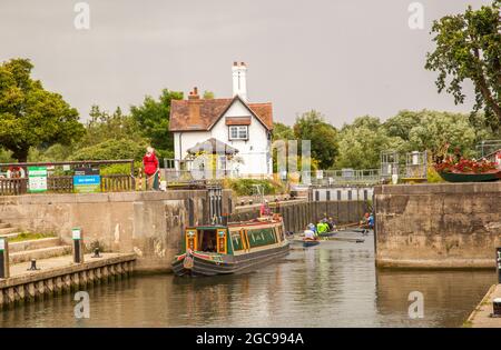 Kanal Schmalboot und Menschen in Ruderbooten, die durch die Schleusen auf der Themse bei Goring Oxfordshire England Stockfoto