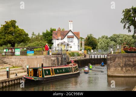 Kanal Schmalboot und Menschen in Ruderbooten, die durch die Schleusen auf der Themse bei Goring Oxfordshire England Stockfoto