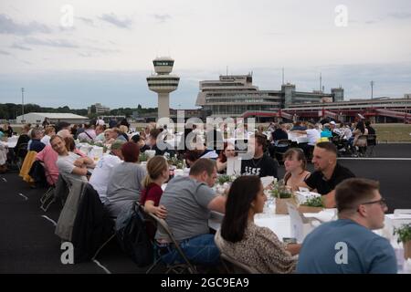 Berlin, Deutschland. August 2021. Die Teilnehmer des „Freedom Dinner“ sitzen an Tischen auf der Startbahn des ehemaligen Flughafens Tegel. Die Wirtschaftsverwaltung, die Senatskanzlei, die Messe Berlin und das Tourismusmarketing hatten zur Open-Air-Veranstaltung eingeladen. Quelle: Paul Zinken/dpa/Alamy Live News Stockfoto