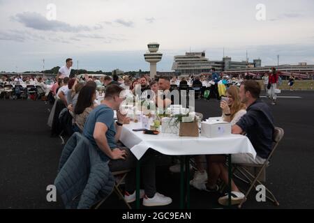 Berlin, Deutschland. August 2021. Die Teilnehmer des „Freedom Dinner“ sitzen an Tischen auf der Startbahn des ehemaligen Flughafens Tegel. Die Wirtschaftsverwaltung, die Senatskanzlei, die Messe Berlin und das Tourismusmarketing hatten zur Open-Air-Veranstaltung eingeladen. Quelle: Paul Zinken/dpa/Alamy Live News Stockfoto