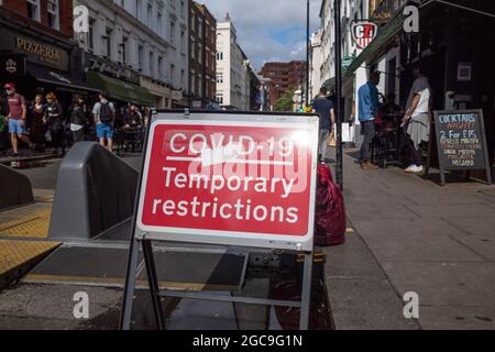 London, Großbritannien. 7. August 2021. Ein Covid-19-Schild mit vorübergehenden Beschränkungen wurde an einem Samstagabend prominent in Soho ausgestellt. Das Vereinigte Königreich verzeichnete im letzten 24-Stunden-Zeitraum weitere 28,612 Coronavirus-Fälle, mit 130,281 Covid-19-Todesfällen seit Beginn der Pandemie. Kredit: Stephen Chung / Alamy Live Nachrichten Stockfoto