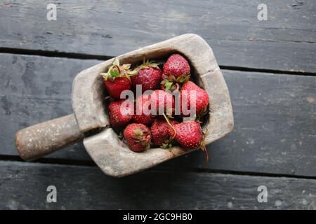 Frische, saftige Erdbeeren in einem alten Holzbehälter. Stockfoto