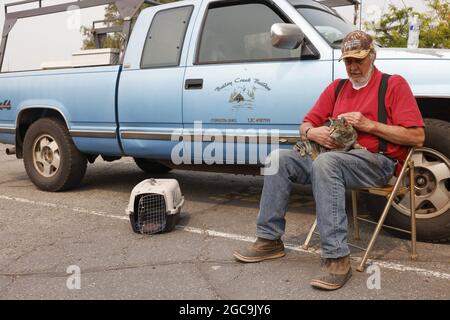 Susanville, Usa. August 2021. Der Evakuierte Jim Cabral aus Westwood, einer kleinen Gemeinde östlich des Lake Amador, tröstet seine Katze Jeff, während sie auf eine Entmachtung durch die Behörden warten, um nach Hause zurückzukehren, während sie im Lassen County Run Evakuierungszentrum an der Lassen High School in Susanville Schutz einräumte, Kalifornien während des Brandes von Dixie am 7. August 2021. Foto von Peter DaSilva/UPI Credit: UPI/Alamy Live News Stockfoto