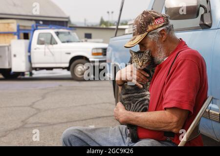 Susanville, Usa. August 2021. Der Evakuierte Jim Cabral aus Westwood, einer kleinen Gemeinde östlich des Lake Amador, tröstet seine Katze Jeff, während sie auf eine Entmachtung durch die Behörden warten, um nach Hause zurückzukehren, während sie im Lassen County Run Evakuierungszentrum an der Lassen High School in Susanville Schutz einräumte, Kalifornien während des Brandes von Dixie am 7. August 2021. Foto von Peter DaSilva/UPI Credit: UPI/Alamy Live News Stockfoto